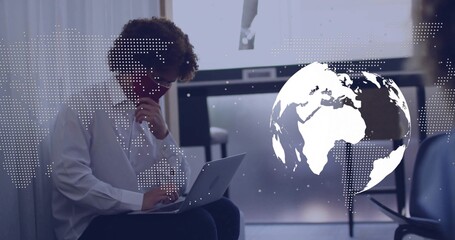 Studying man in white shirt typing on laptop in conference room with globe overlay