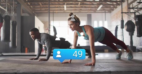 Performing partners holding planks in athletic wear in gym, with hanging bags, blue bubble 49