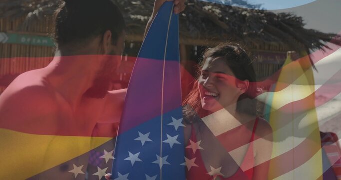 Smiling shirtless man holding blue star surfboard, woman wearing red swimsuit at beach with flags - Powered by Adobe