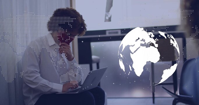 Studying man in white shirt typing on laptop in conference room with globe overlay