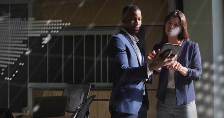 Viewing tablet, two professionals in navy attire pointing in conference room with glass reflections