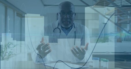 Gesturing senior doctor explaining care in clinic, wearing white lab coat, stethoscope, data charts