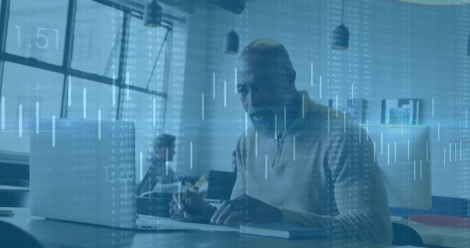 Working man wearing sweater typing on laptop at modern office desk, with notebook and data overlay