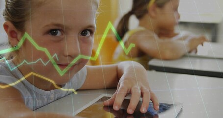 Touching tablet, girl in sleeveless top working at school desk with second tablet, graph overlays