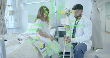 Examining doctor wearing coat and stethoscope, holding crutch beside child in gown on hospital bed