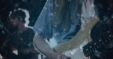 Fototapeta premium Strumming guitarist in faded denim shirt playing electric guitar on dim stage, with Bitcoin bubbles