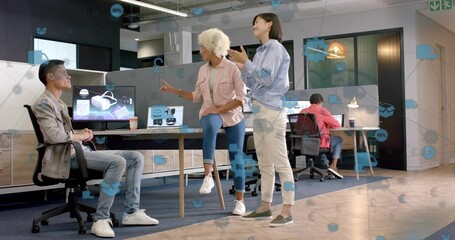 Presenting team wearing casual wear reviewing VR in open office, monitor showing headset