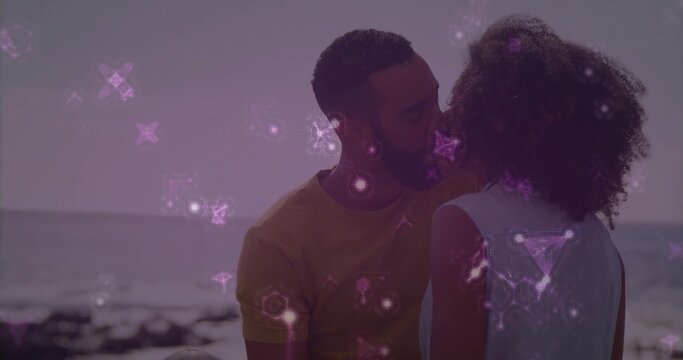 Holding hands couple wearing sleeveless top and mustard tee standing at beach, purple star overlay