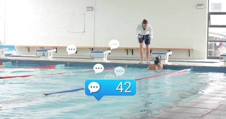 Leaning female coach in hoodie coaching swimmer with cap at community pool, overlays 42, copy space