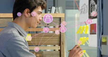 Arranging designer in gray shirt organizing yellow notes on glass board at studio with pink overlay