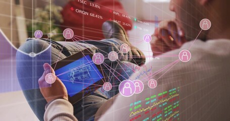 Reclining adult man in jeans and sweater holding tablet at home, senior woman viewing AR overlays