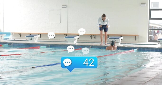 Leaning female coach in hoodie coaching swimmer with cap at community pool, overlays 42, copy space