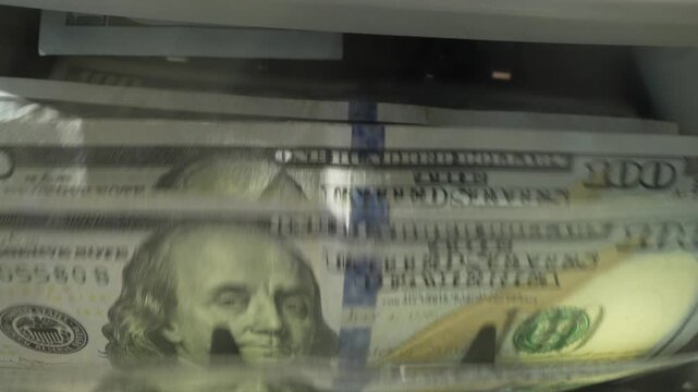 Finance and cash dollars concept. Counting dollars with electronic money counter machine. 100 dollar bills counted in money counting machine. Cash money dollars into banknote counter.