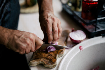 Chef prepares fresh ingredients by finely chopping red onions