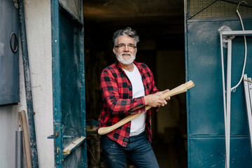 Craftsman stands proudly at workshop door holding wooden tool