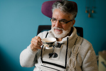 Elderly man enjoying tea while seated in a cozy room