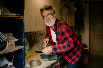 Elderly man smiles while working on a woodworking project