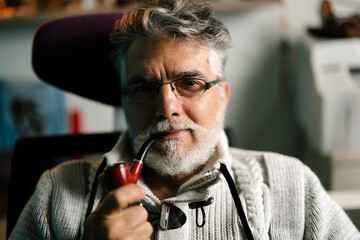 Experienced man with glasses enjoys pipe smoking