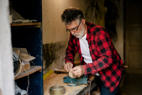 Craftsman skillfully carving wood in a workshop filled with tools
