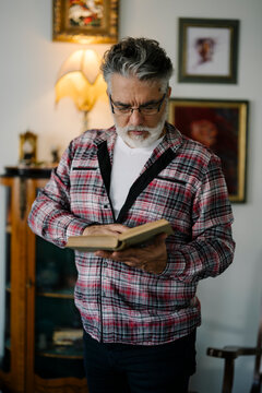 Elderly man reading a book in a cozy living room