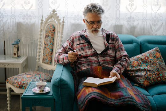Elderly man reading a book while cozying up in a colorful living room