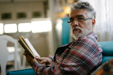 Older man reading a book while relaxing on a couch