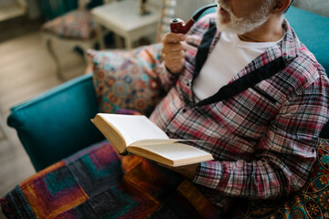 Senior man enjoys reading a book while relaxing on a colorful couch