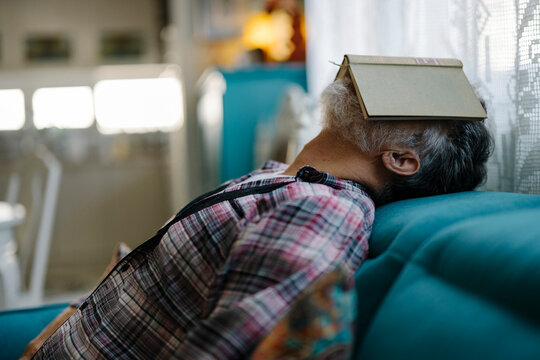 Relaxing scene with an older man resting on a couch with a book