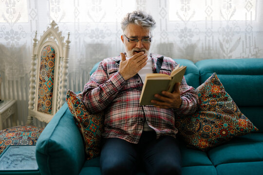 Senior man enjoys reading an interesting book while relaxing - Powered by Adobe