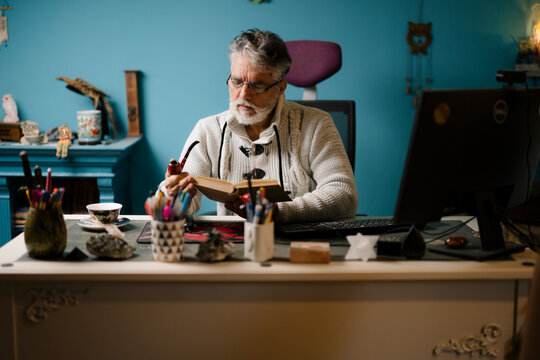 Senior man reading in a cozy home office with blue walls