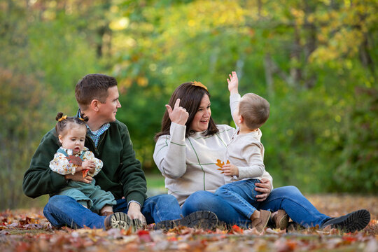 A young family explore fallen leaves in autumn