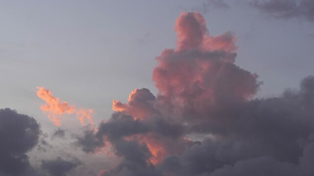 Colorful clouds at sunset with shades of pink and gray. The sky is partially cloudy, creating a serene atmosphere.