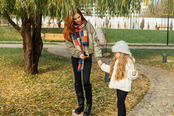 Mother and daughter exploring autumn park, surrounded by yellow leaves. Cozy outfits, playful moment, seasonal bonding outdoors.