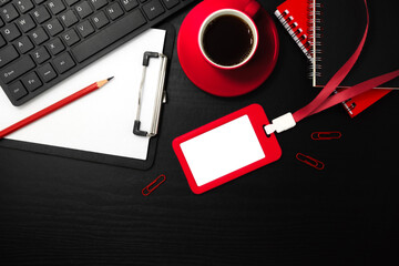 Red plastic badge with stationery and coffee on black wooden texture background. Template designed for employees of company