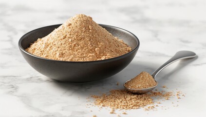 Peanut powder in black bowl with spoon on white marble surface