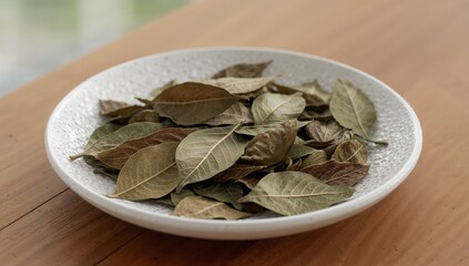 Dried culinary leaves in a white bowl on a rustic wooden table