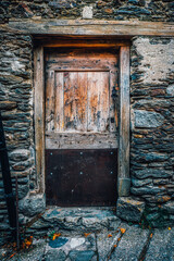 Old Wooden Door with Metal Plate in Traditional Stone Wall Facade
