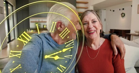 Seniors leaning, man reaching for selfie on couch, tech gold clock overlaying faces, marking moment - Powered by Adobe