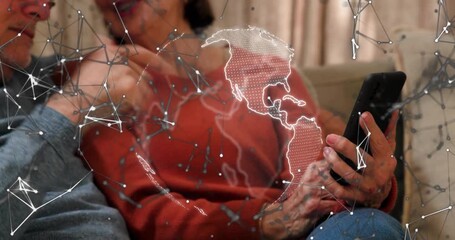 Senior couple leaning on sofa with man pointing initiating phone tapping and exploring tech globe