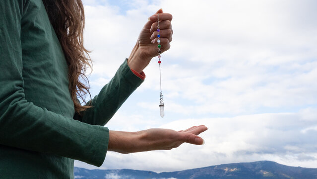 Woman holding crystal pendulum for dowsing and spiritual healing
