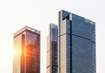Obraz premium Modern Glass Skyscrapers Against a Bright Sky with Sun Flare