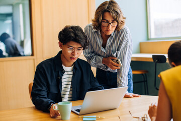 Young coworkers reviewing a project on laptop in a modern office space