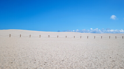 Sand dunes by the sea in Leba, Slowinski National Park, Poland. Safety barriers constructed of wooden posts and ropes. Beautiful desert landscape