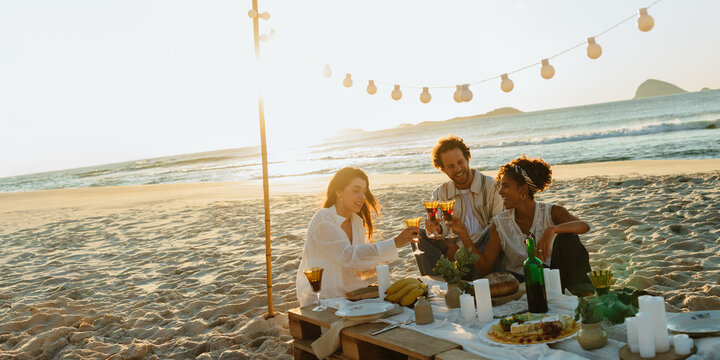 Friends celebrate at beach dinner under string lights