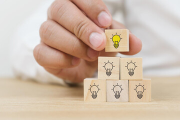 Creative idea, solution and innovation concept. Idea generation and screening for product development process. Wooden blocks with light bulb and yellow color icons on clean background and copy space
