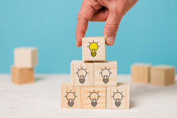 Creative idea, solution and innovation concept. Idea generation and screening for product development process. Wooden blocks with light bulb and yellow color icons on clean background and copy space