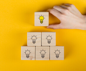 Creative idea, solution and innovation concept. Idea generation and screening for product development process. Wooden blocks with light bulb and yellow color icons on clean background and copy space