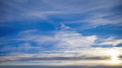 Obraz premium Soft cirrus clouds stretch across a blue sky at sunset, creating a calm and airy natural background.