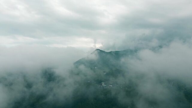 A dramatic drone view of mountains hidden behind thick fog and low clouds. Towering mountain peaks are faintly visible in the distance in Tawangmangu, Central Java, on Saturday, October 25, 2025.