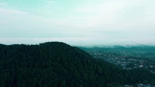 Aerial view of a lush green forest hillside with a cityscape covered in morning mist, creating a serene in Tawangmangu, Central of Java, on Saturday, October 25, 2025.	
